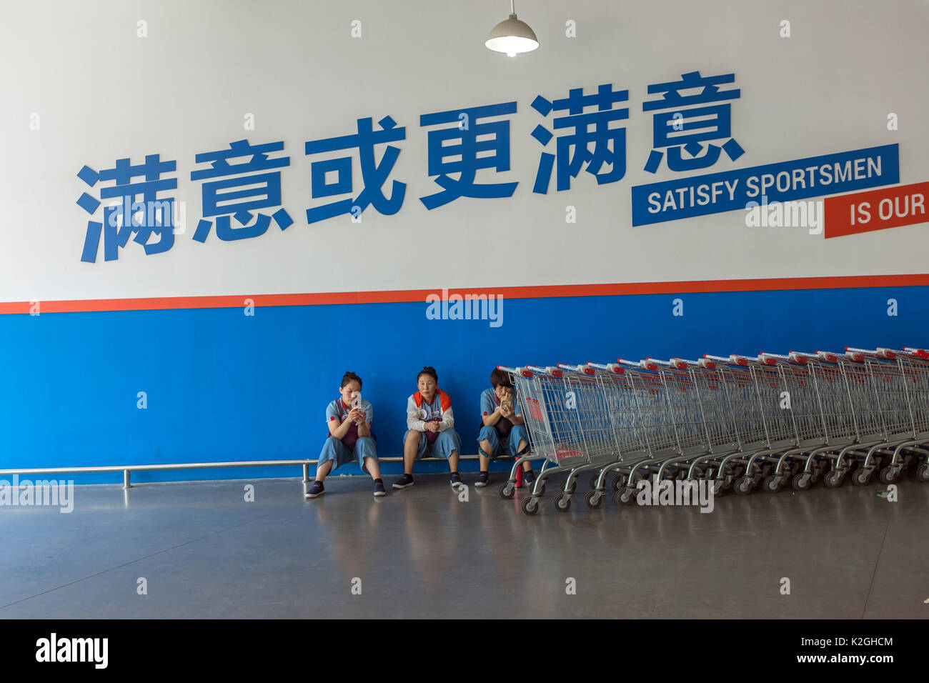 Chinesische Mitarbeiterinnen Rest unter einem Slogan einen Carrefour Markt in Peking, China. 30-Aug-2017 Stockfoto