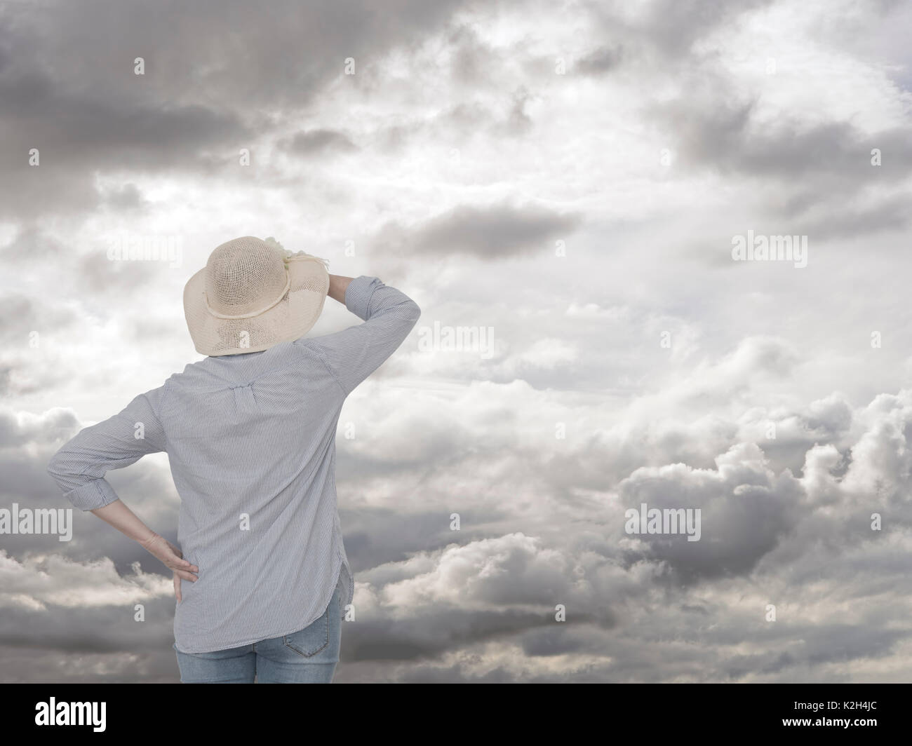 Frau auf der Suche nach Wolken. Regentag auf dem Weg. Zukunftssicherheit Konzept. Stockfoto