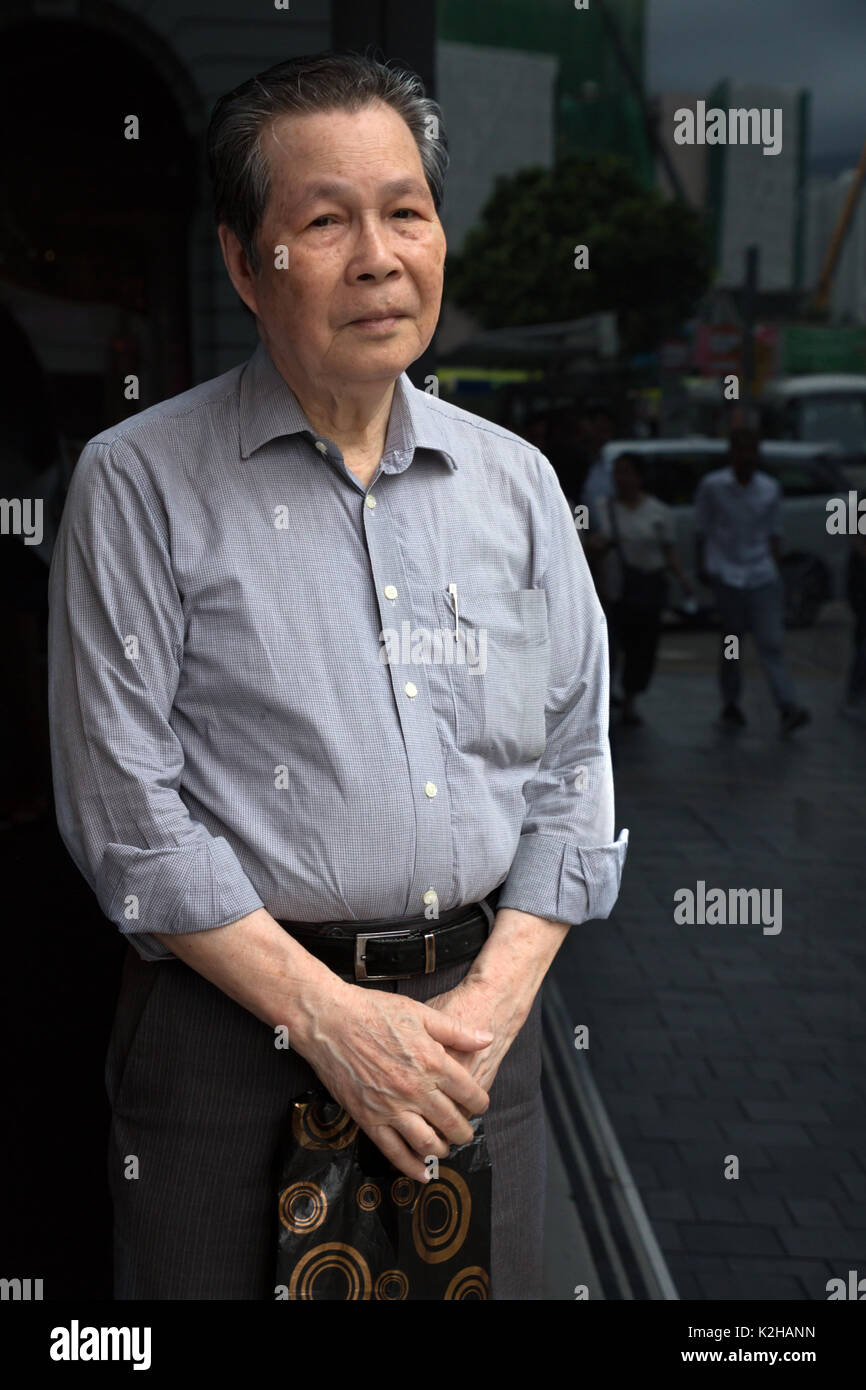 Alte chinesische Mann in den Straßen von Hong Kong posierend Stockfoto