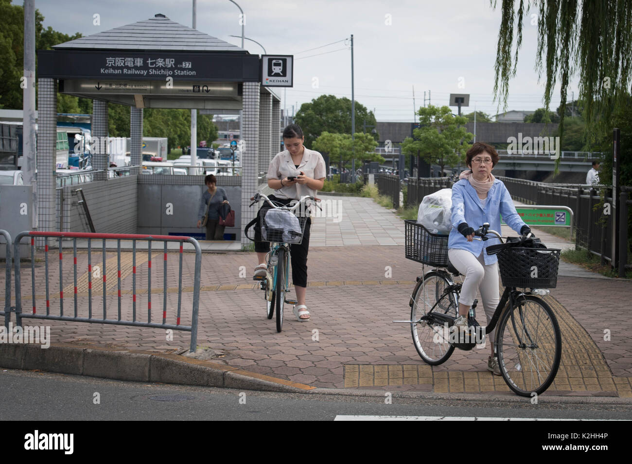 Zwei Frauen auf Fahrrädern warten die Straße in dieses Bild von einem Fahrzeug in Premierminister Theresa's Mai motorcade genommen, als sie in Kyoto, Japan ankommt. Stockfoto