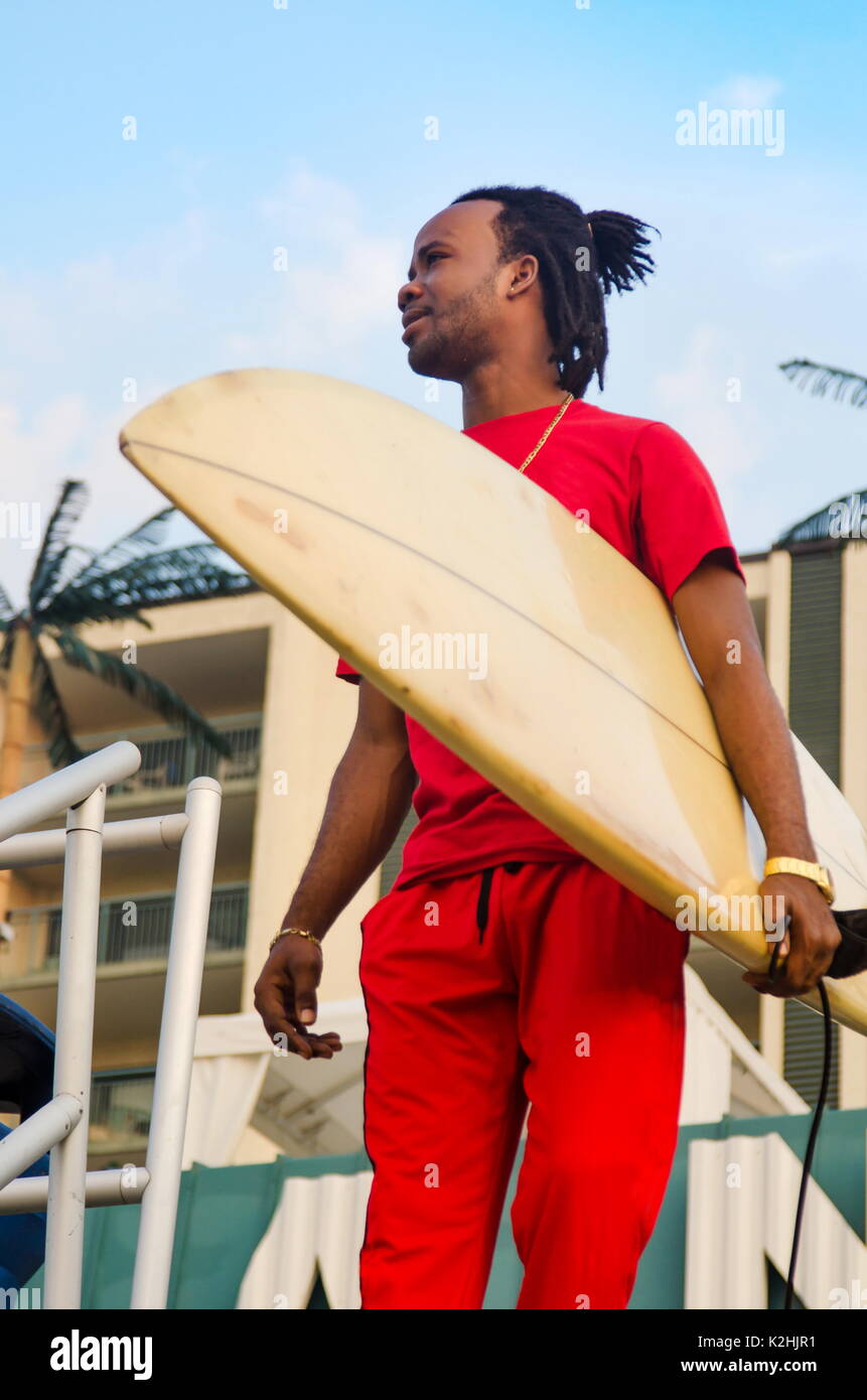 Junge afrikanische amerikanische Mann mit einem Surfbrett draußen Stockfoto