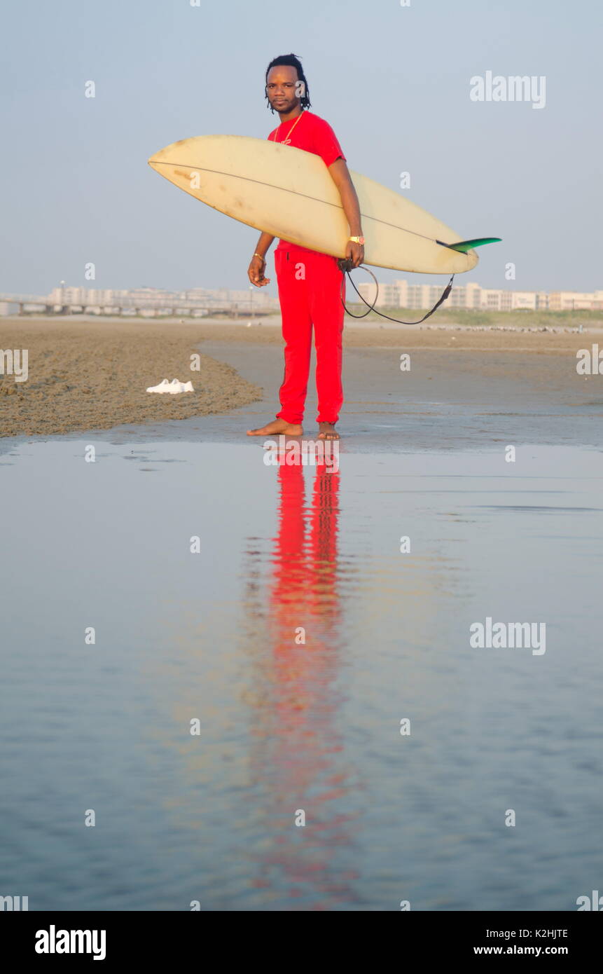 Mann mit einem Surfbrett am Strand mit ruhigem Meer Stockfoto