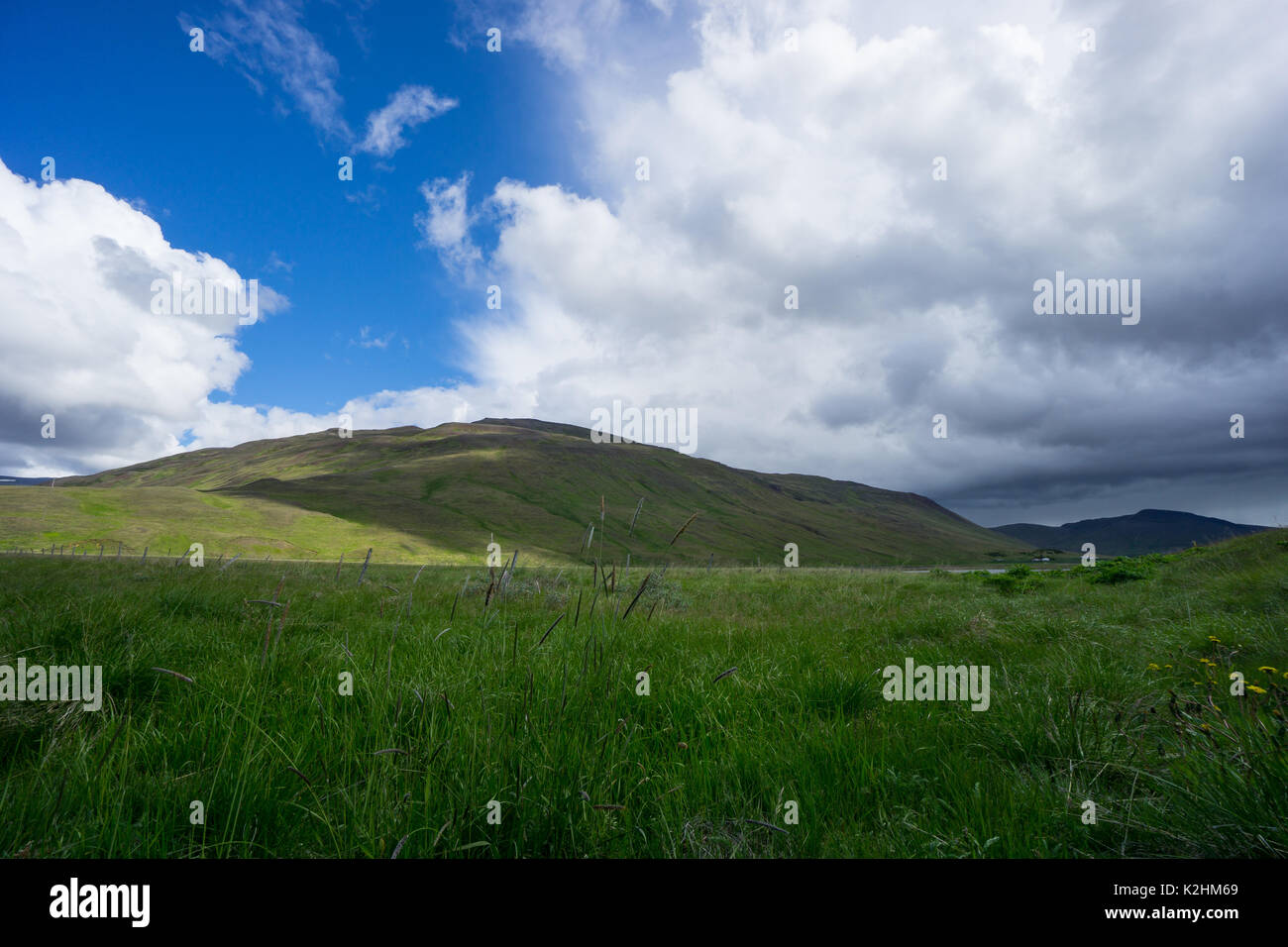 Island - dramatische Himmel als Gewitter kommt über endlose grüne Berge und Felder Stockfoto