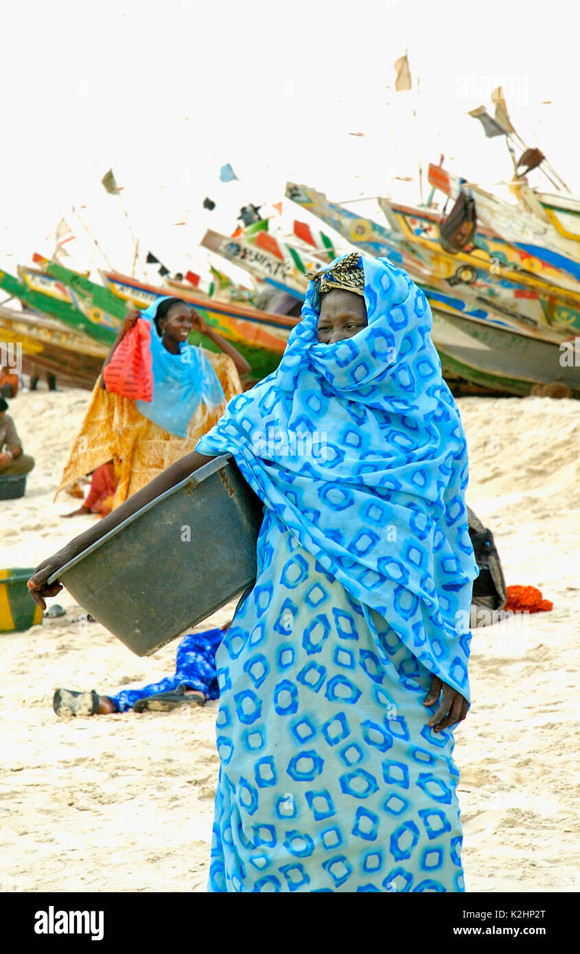 Eine Frau wartet auf die Fischerboote auf den Strand in Nouakchott, Mauretanien Stockfoto