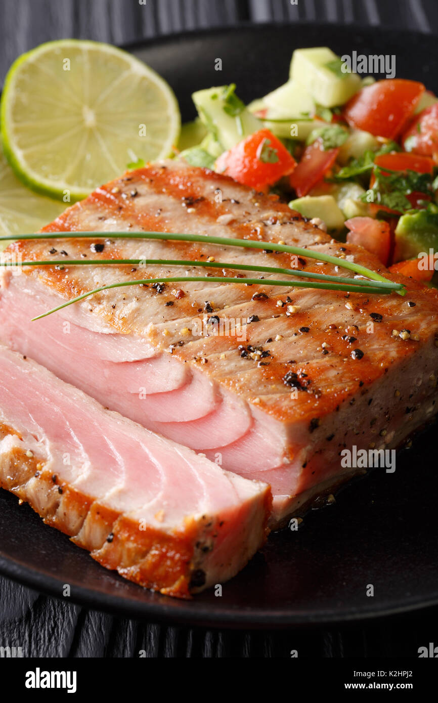Schöne gegrillter Thunfisch Filet mit Kalk und Avocado salsa Closeup auf einem Teller. Vertikale Stockfoto