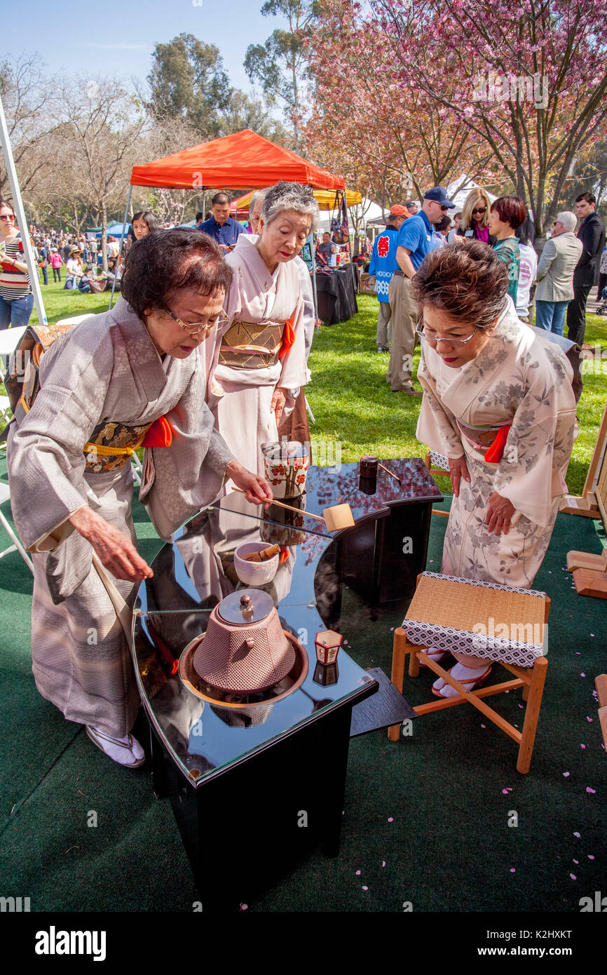 Traditionell japanische Frauen in Kimonos gekleideten demonstrieren die Omotesenkei Tee Zeremonie in Huntington Beach, CA. Diese aufwändige und raffinierte Japanische Tee Zeremonie soll Respekt durch die Gnade und die Etikette zu demonstrieren. Hinweis Bambus Tee Haus wall. Stockfoto