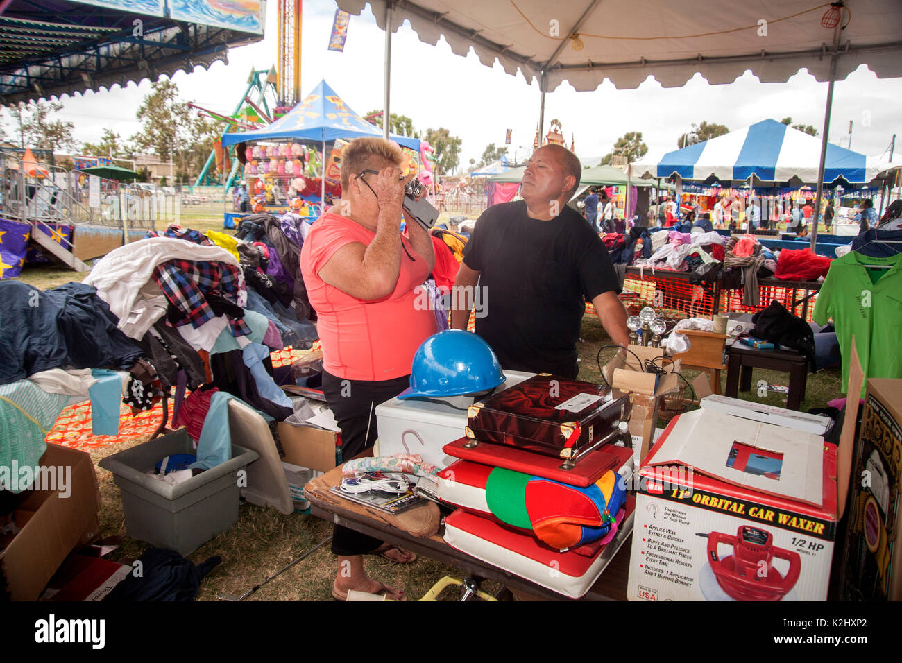 Eine kräftige Hispanic Frau versucht, auf ein paar Witz Brillen in einem Vergnügungspark Trödelmarkt in Costa Mesa, CA. Hinweis Vielfalt von Objekten zum Verkauf angeboten. Stockfoto