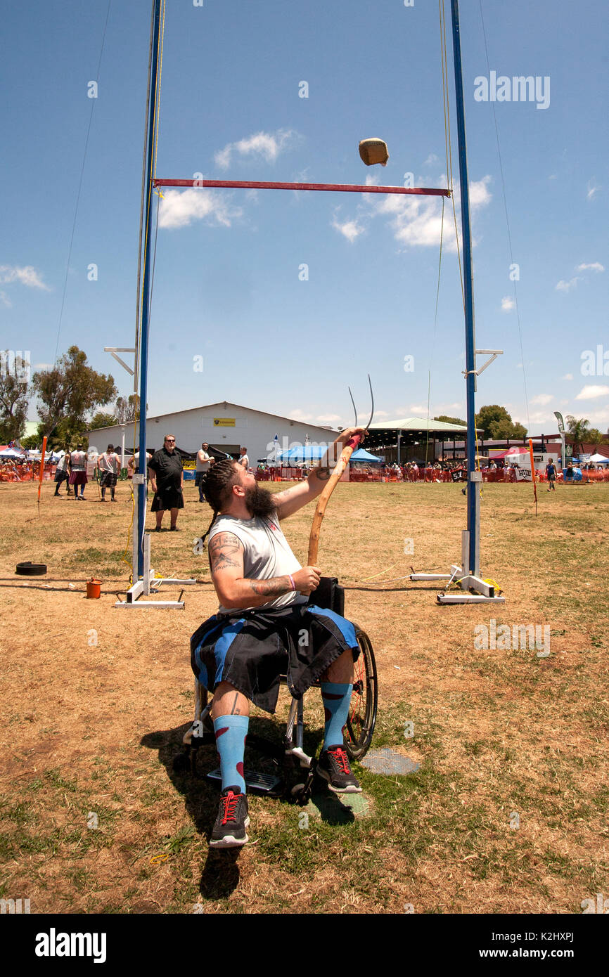 Einen kilted jungen Mann im Rollstuhl konkurriert in der "heaf Werfen' an einem schottischen Festival in Costa Mesa, CA, mit einer Heugabel einen 16-pound Sackleinen Tasche von Stroh über eine Bar zu werfen. Stockfoto