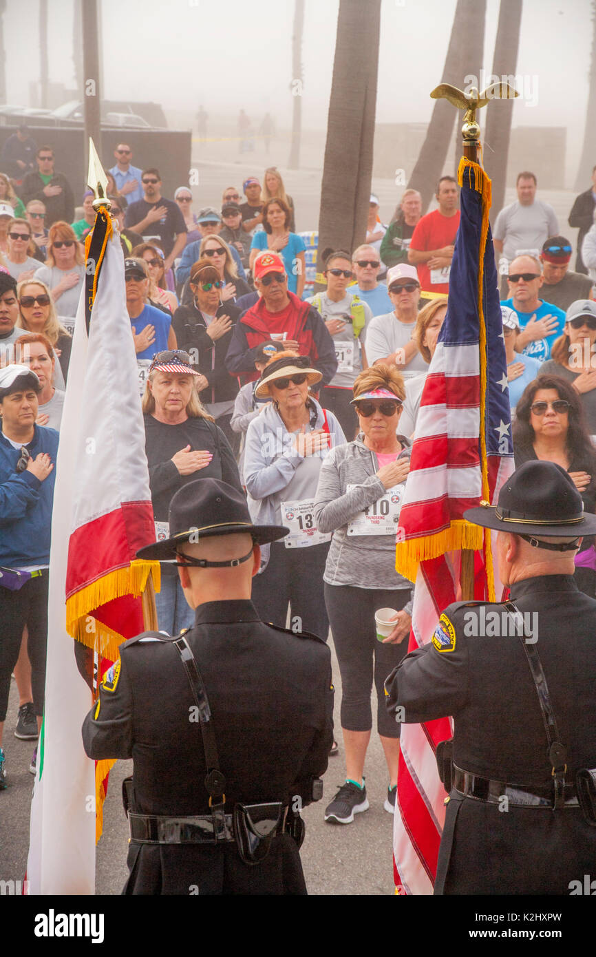 Multirassischen militärische Frauen begrüssen die US-Flagge zwar eine Hommage von Zuschauer und Teilnehmer vor konkurrieren in einem Wettlauf im Huntington Beach, CA. Stockfoto
