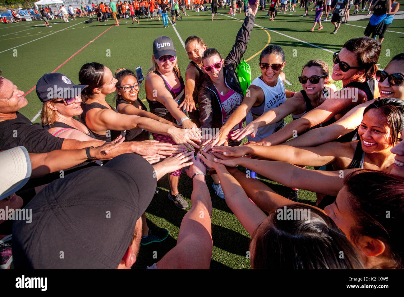 Enthusiastisch multirassischen Mitgliedern der Frauen Titel Team berühren die Hände in einer Demonstration der Solidarität und der gegenseitigen Unterstützung, bevor ein Wettlauf in Costa Mesa, CA. Stockfoto