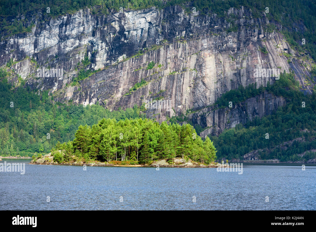 Kleiner Wald Insel mit massiven vertikalen Berg im Hintergrund. Lage Fluss Otra in Südnorwegen. Stockfoto