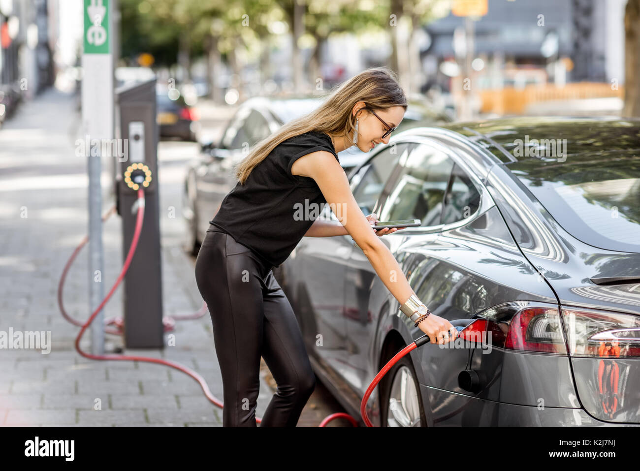 Frau aufladen elektrischen Auto im Freien Stockfoto