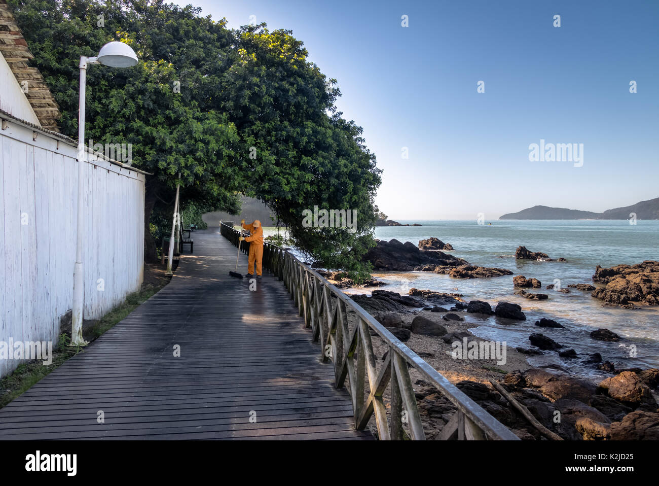 Hausmeister fegt eine hölzerne walkay - Balneário Camboriú, Santa Catarina, Brasilien Stockfoto