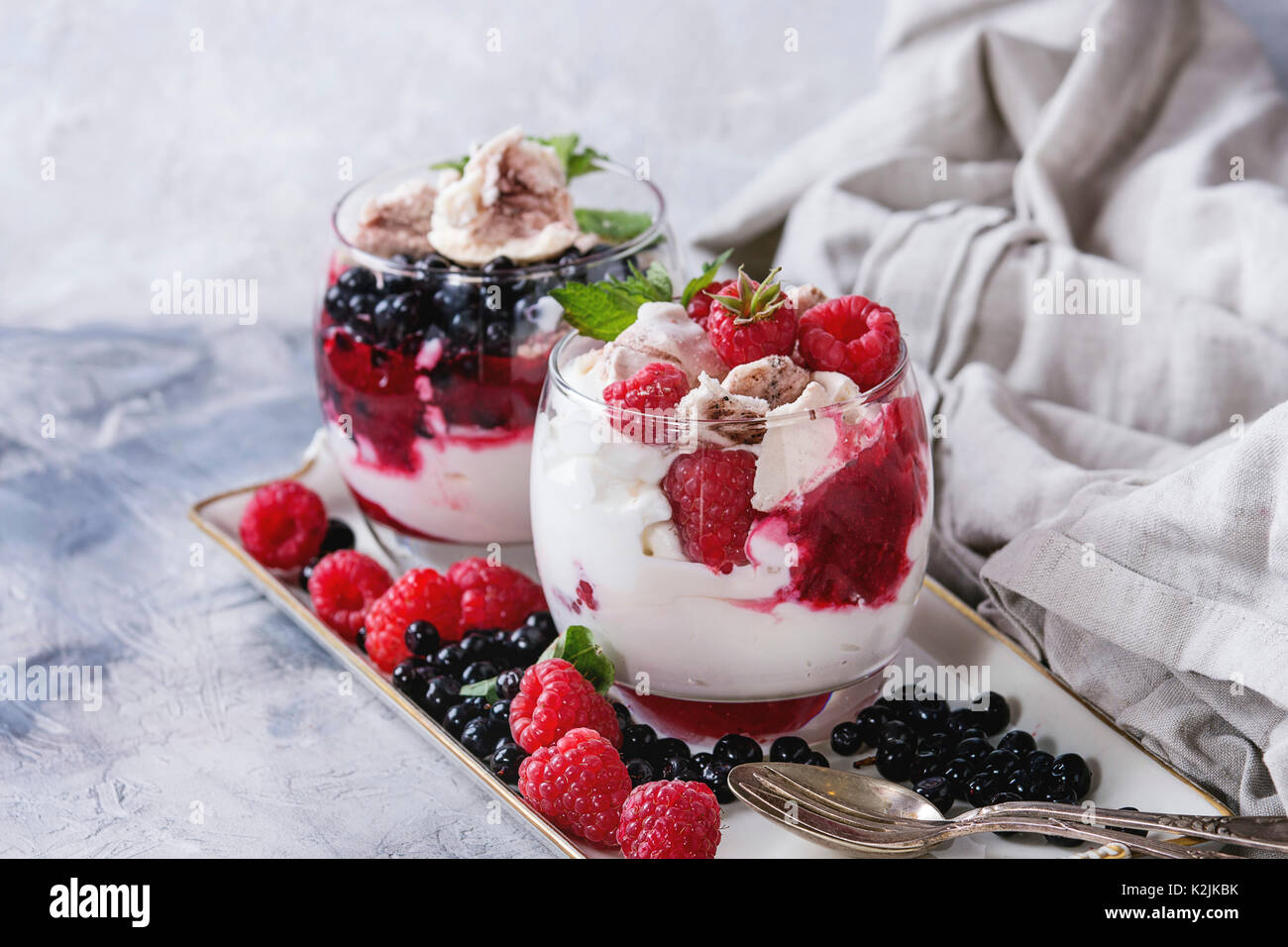 Traditionelle Sommer dessert Eton Mess. Gebrochene Meringue mit Schlagsahne, Beeren Marmelade, frischen Heidelbeeren und Himbeeren in zwei Gläser, dekoriert mit Stockfoto