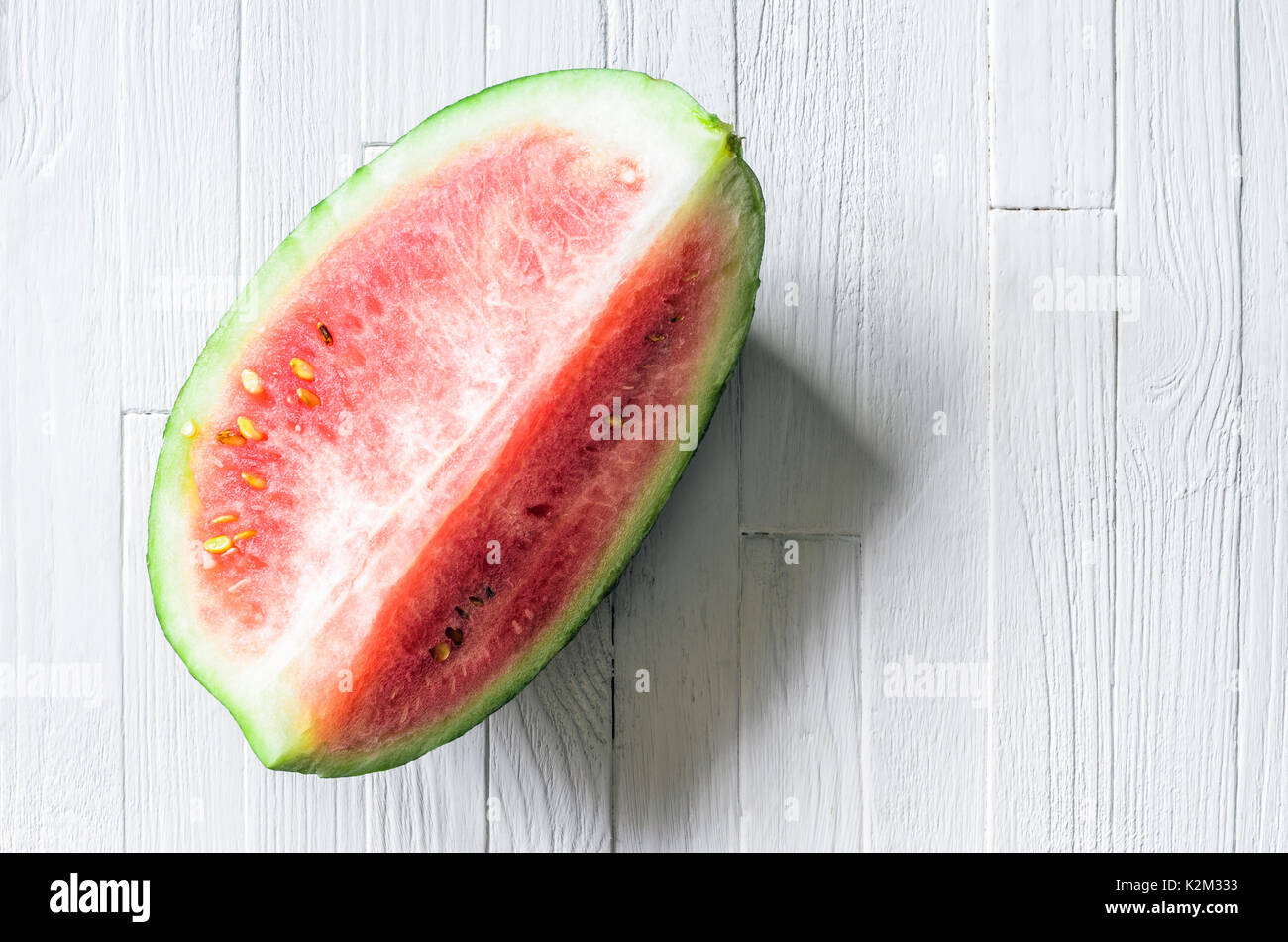 Ein Viertel einer Wassermelone auf weißem Holz Hintergrund der Ansicht von oben. Stück frische Wassermelone auf weißen Tisch mit leeren Raum für Text. Leere Hintergrund Stockfoto