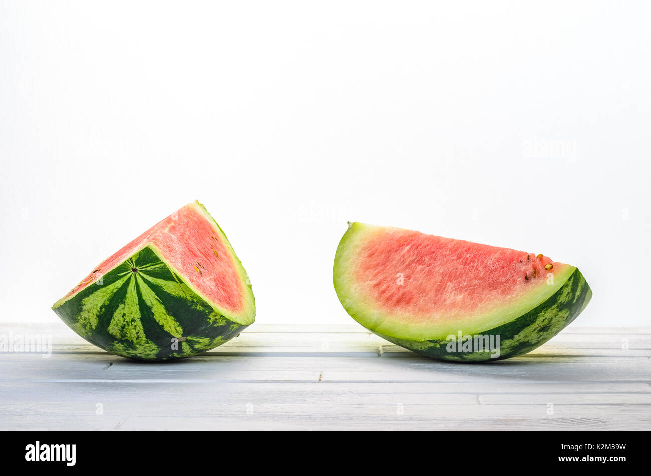 Zwei Stücke einer Wassermelone auf weissem Holztisch auf weißem Hintergrund Hintergrund der Vorderansicht. Leere minimalistischen Hintergrund Stockfoto