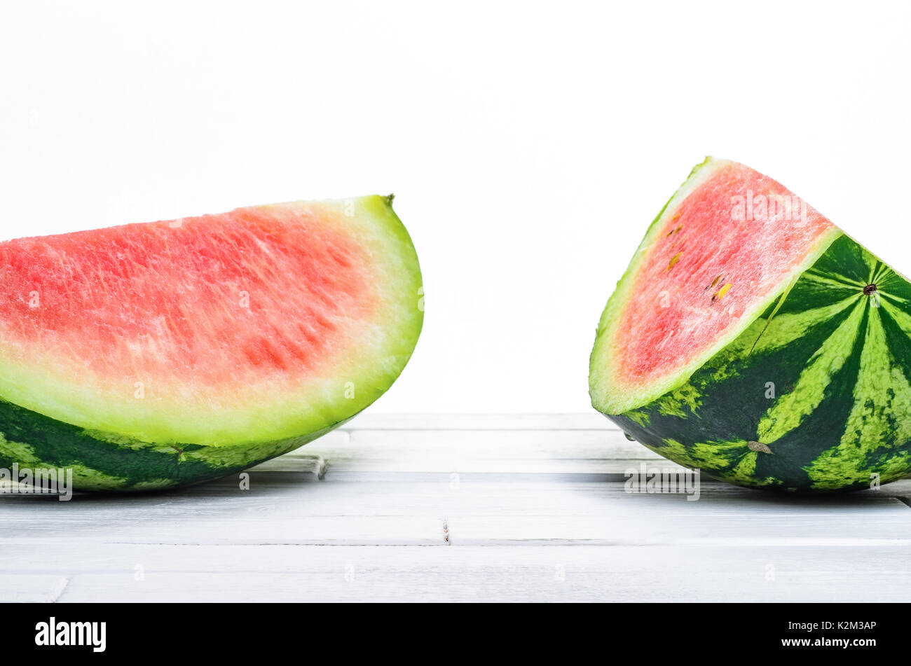 Zwei Stücke einer Wassermelone auf weissem Holztisch auf weißem Hintergrund Hintergrund der Vorderansicht. Leere minimalistischen Hintergrund Stockfoto