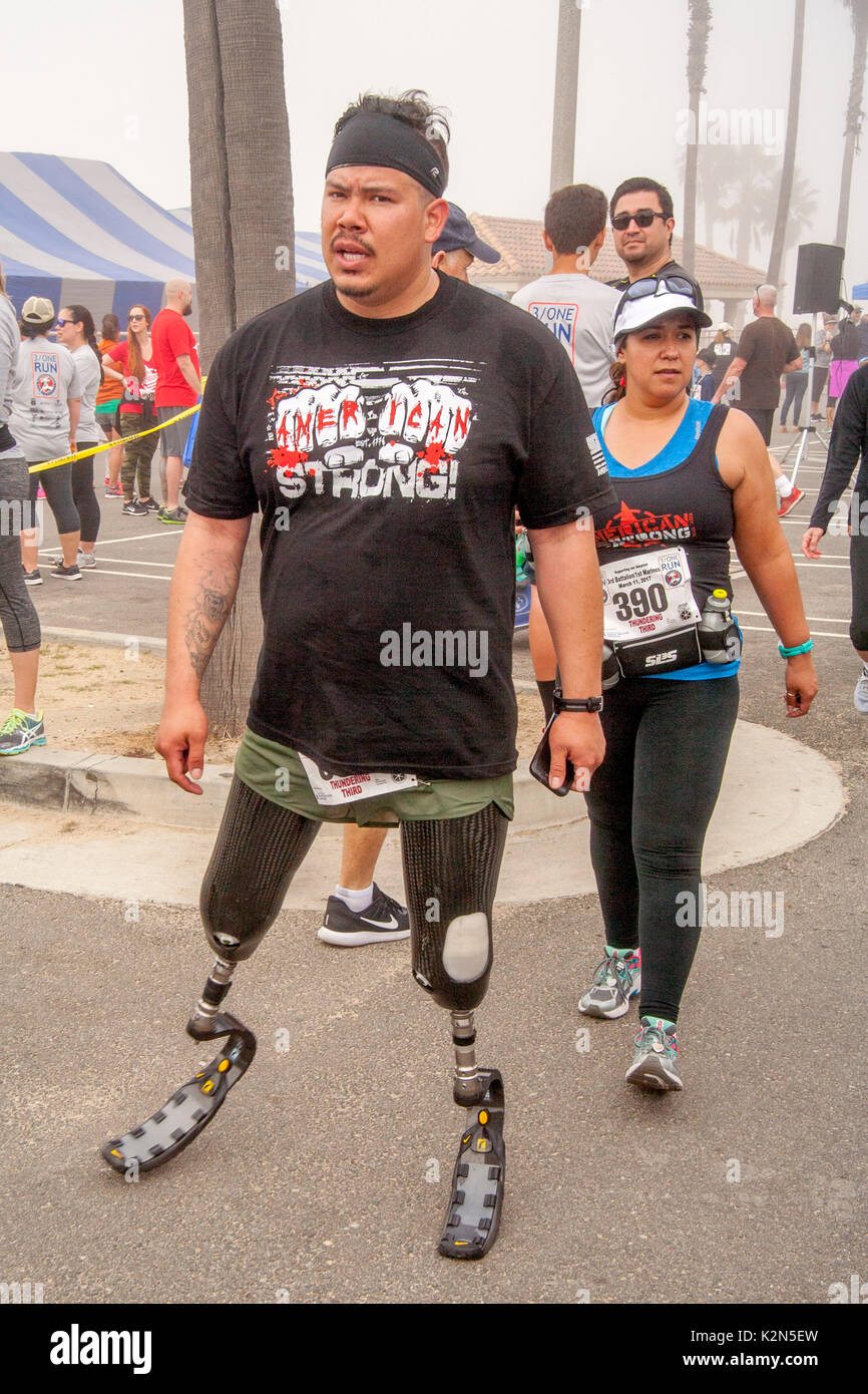 Ein stolzer Spanischer doppeltes amputee tragen prothetische Knie und Füße Fänge sein Atem nach dem Überqueren der Ziellinie auf Gemeinschaftsebene Wettlauf im Huntington Beach, CA. Stockfoto