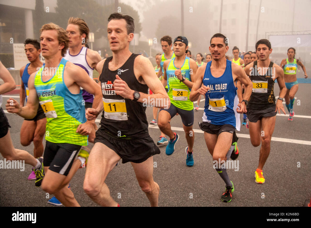 Multirassischen erwachsene Sprint von der Startlinie in einer frühen Morgen Wettlauf auf einer Straße in Newport Beach, CA. Stockfoto