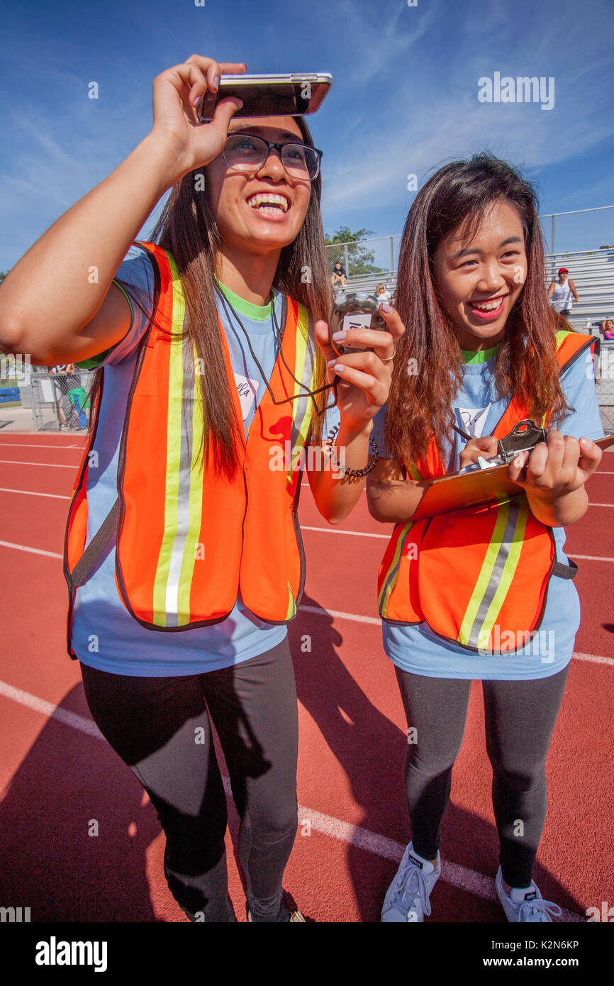 Exuberant Asiatische amerikanische Zeitmesser watch ein Wettlauf auf eine Laufstrecke in Costa Mesa, CA beginnen. Hinweis Zwischenablage und Diagramm. Stockfoto