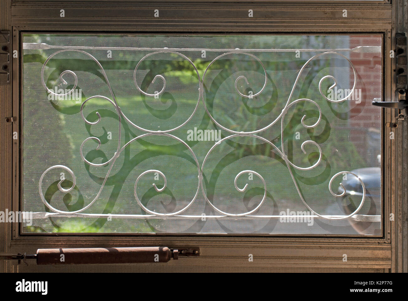 Mitte des Jahrhunderts dekorative-Gitter auf ein Fenster in der Tür mit Gras und eine Terrasse hinter sich Stockfoto