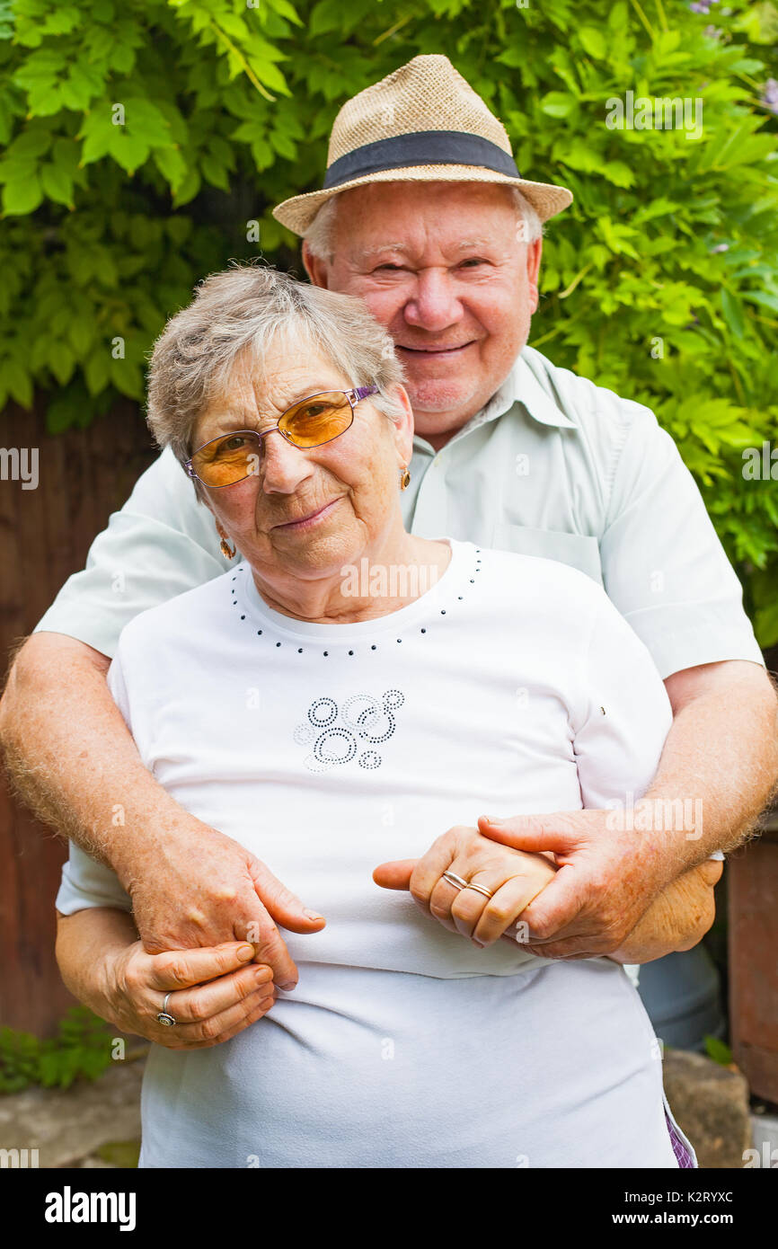 Nettes älteres Paar in Liebe umarmen und lächelnd Outdoor im grünen Garten Stockfoto