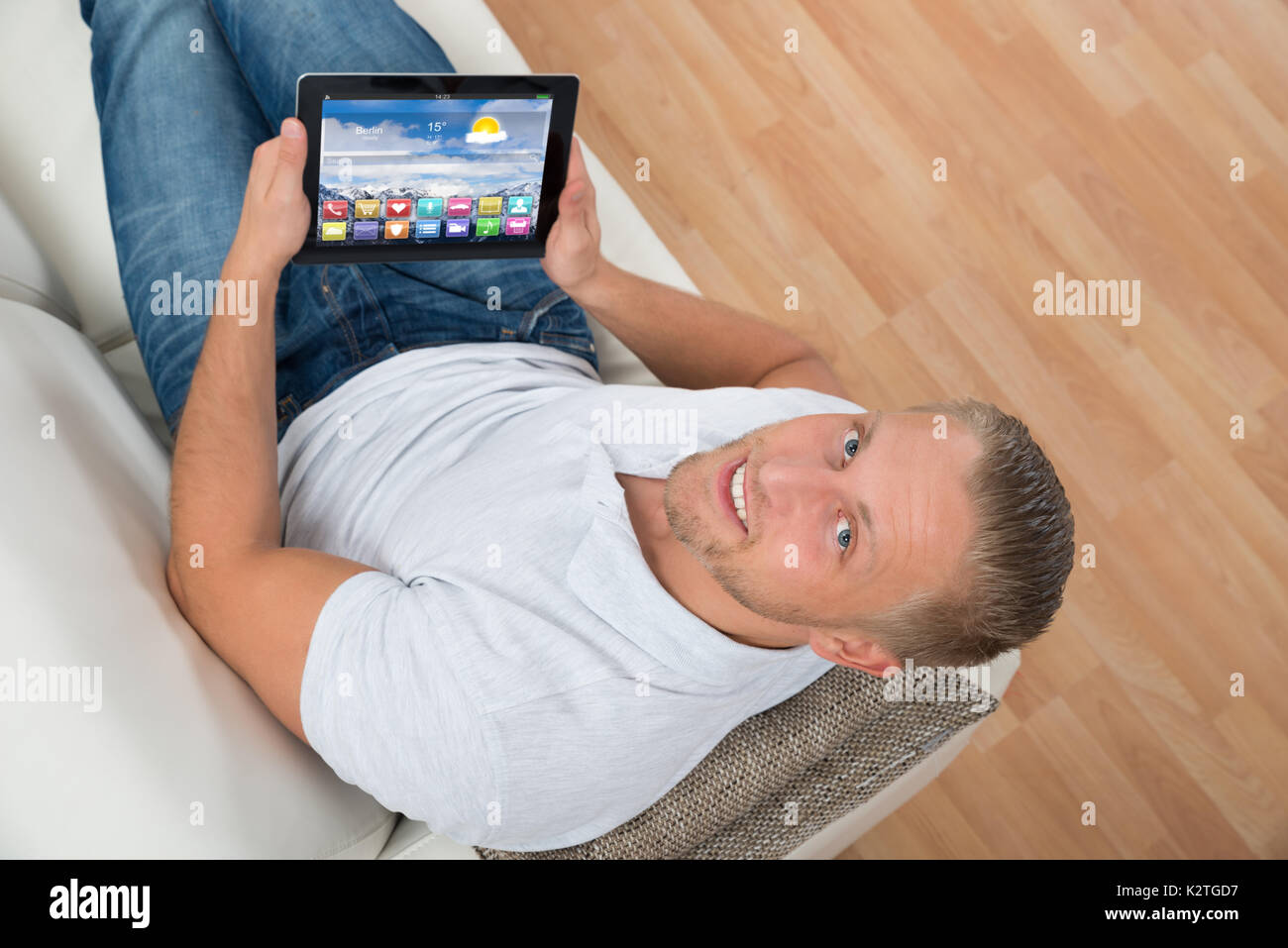 Junge glücklich Mann sitzt auf einem Sofa mit Laptop Symbole angezeigt. Stockfoto