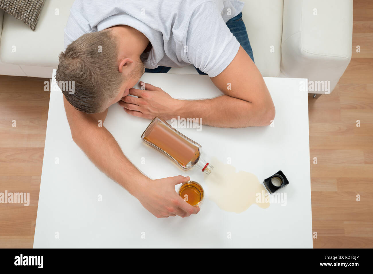 Junge betrunkene Menschen schlafen auf Tabelle mit Alkohol Flasche und Glas Stockfoto