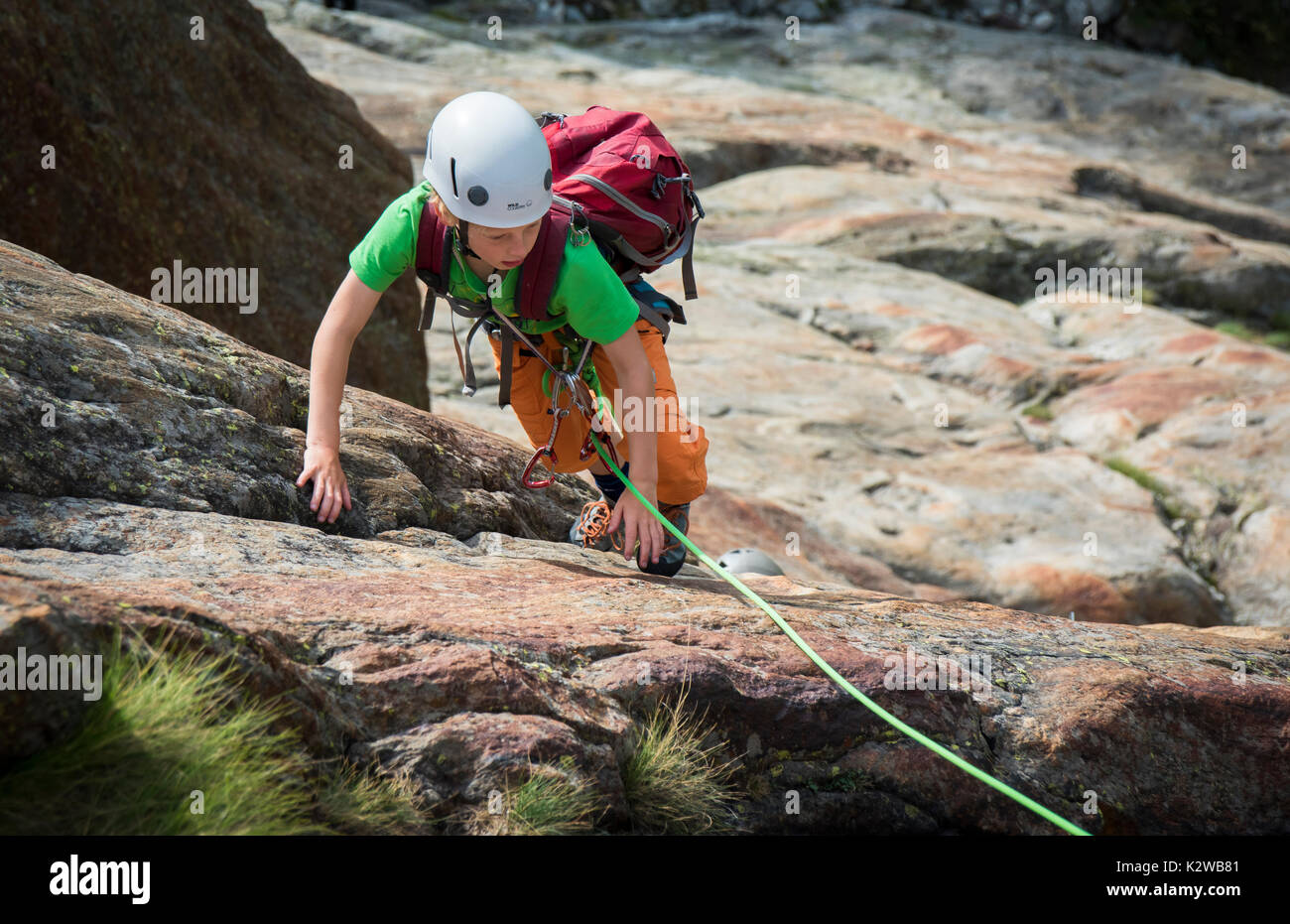 Ein Junge Klettern auf den Platten an der Burghutte in Fieschertal Stockfoto