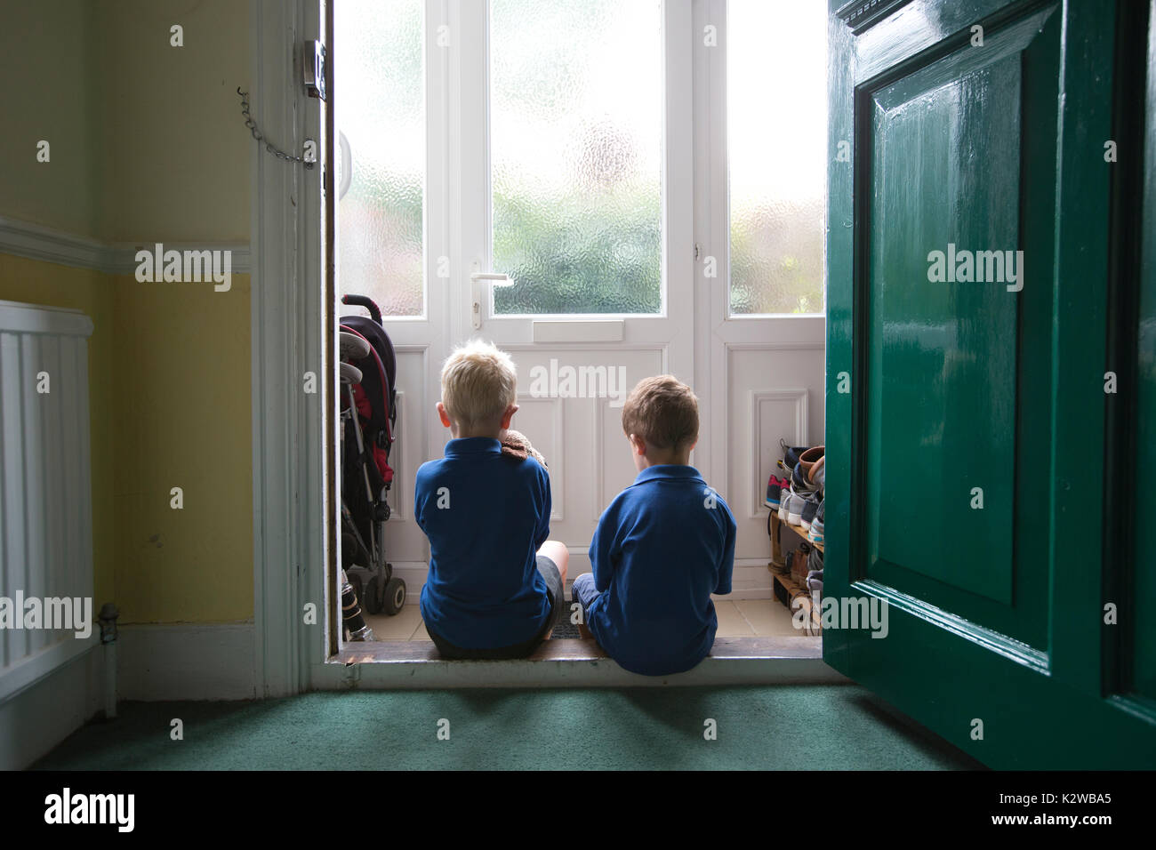 3 Jahre alt und 6 Jahre alten Jungen in einem Wohngebiet Tür gekleidet in Uniform bereit zurück zu Schule, London, England zu gehen, sitzen, Großbritannien Stockfoto