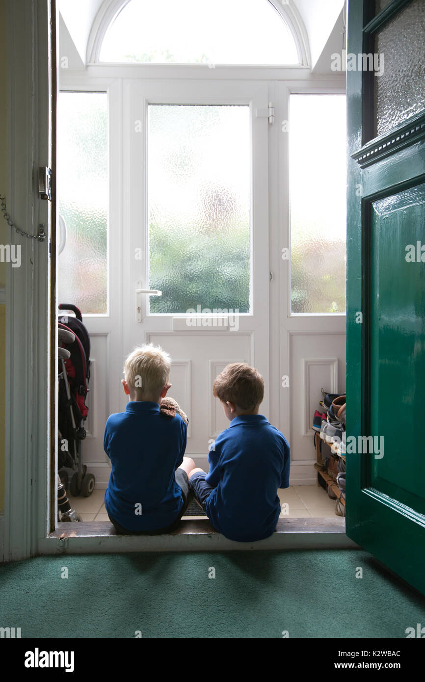 3 Jahre alt und 6 Jahre alten Jungen in einem Wohngebiet Tür gekleidet in Uniform bereit zurück zu Schule, London, England zu gehen, sitzen, Großbritannien Stockfoto