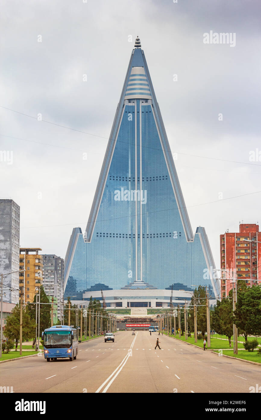 Straße mit Bus und Menschen in der Innenstadt von Pyongyang, Nordkorea mit dem Wahrzeichen Ryugyong Hotel im Hintergrund. Stockfoto