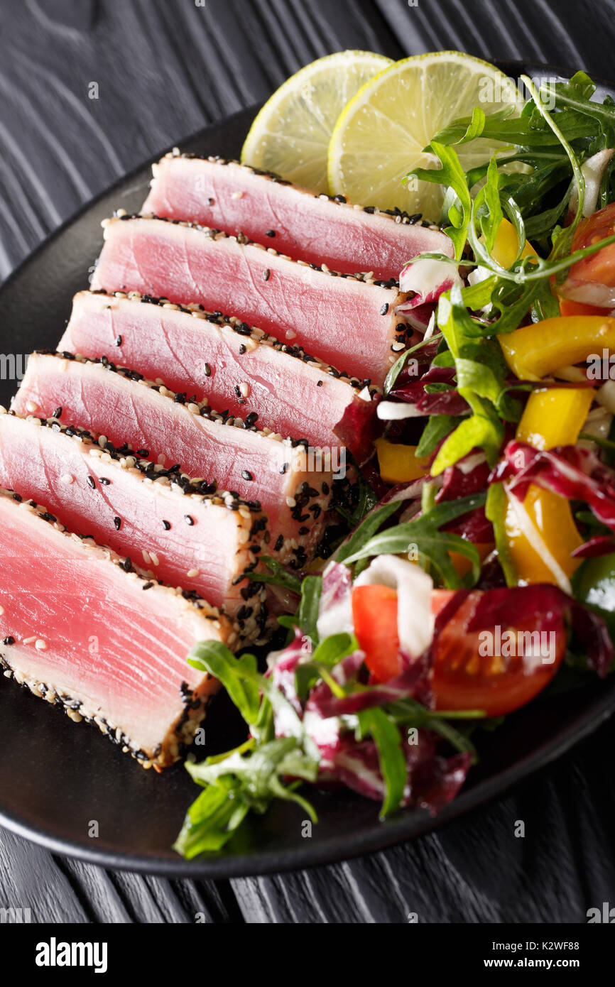 Nahaufnahme von seltenen gebratener Ahi-Thunfisch Scheiben mit frischem Gemüse Salat auf einen Teller. Vertikale Stockfoto