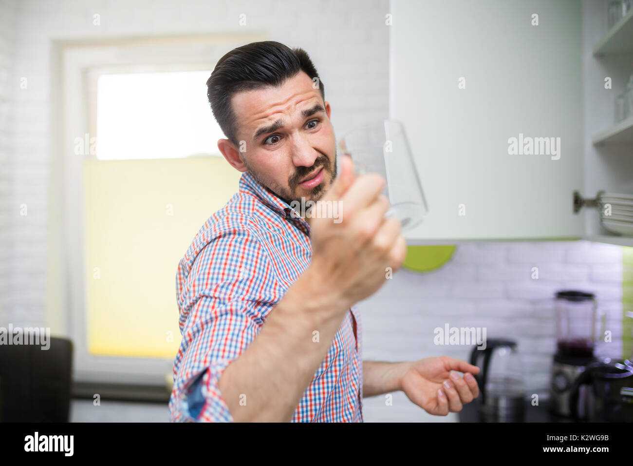 Junge angewidert Mann mit schmutzigen Glas und es zu betrachten. Stockfoto