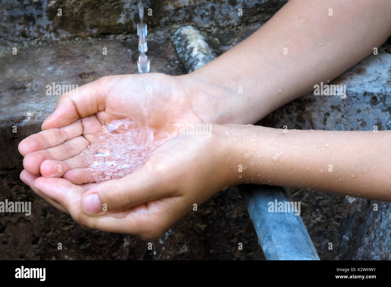 Junge Sammeln von Wasser in seinen Händen am alten Springbrunnen.. Stockfoto