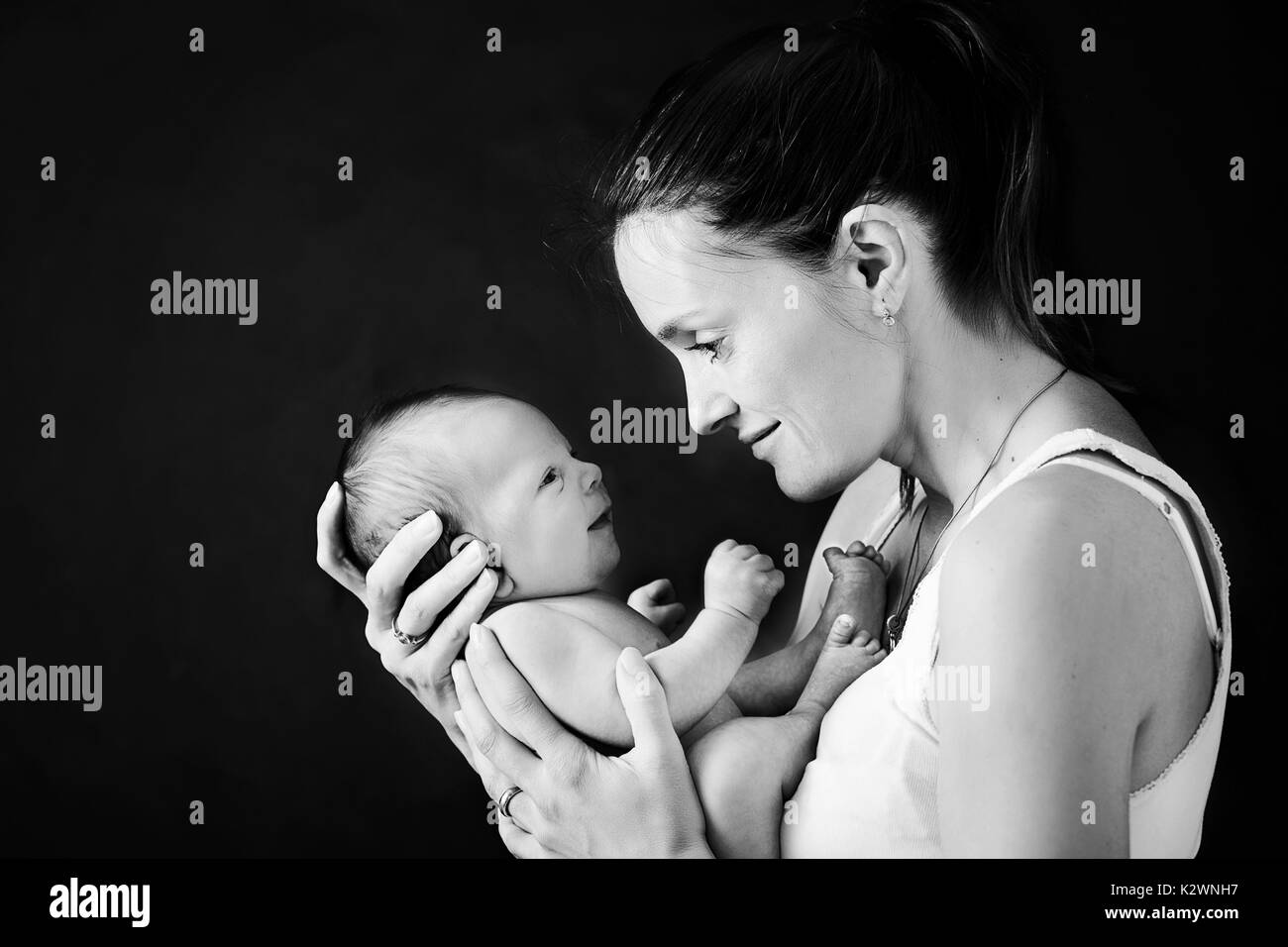 Junge Mutter, küsste und umarmte ihre neugeborenen Jungen, zarten, Fürsorge, Liebe, positive Emotionen. Isolierte Bild, schwarzer Hintergrund, Mutterschaft Konzept, f Stockfoto
