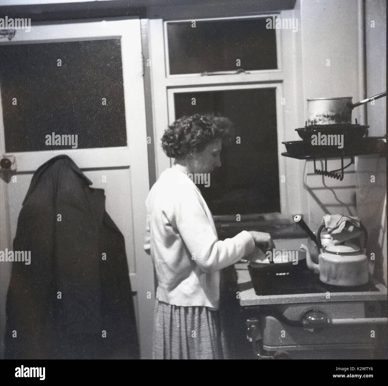1960, historische, Bild einer Dame kochen auf ihren Selbst auf einem  Gasherd in einem kleinen und einfachen Küche auf der Rückseite eines  Reihenhauses, England, UK Stockfotografie - Alamy