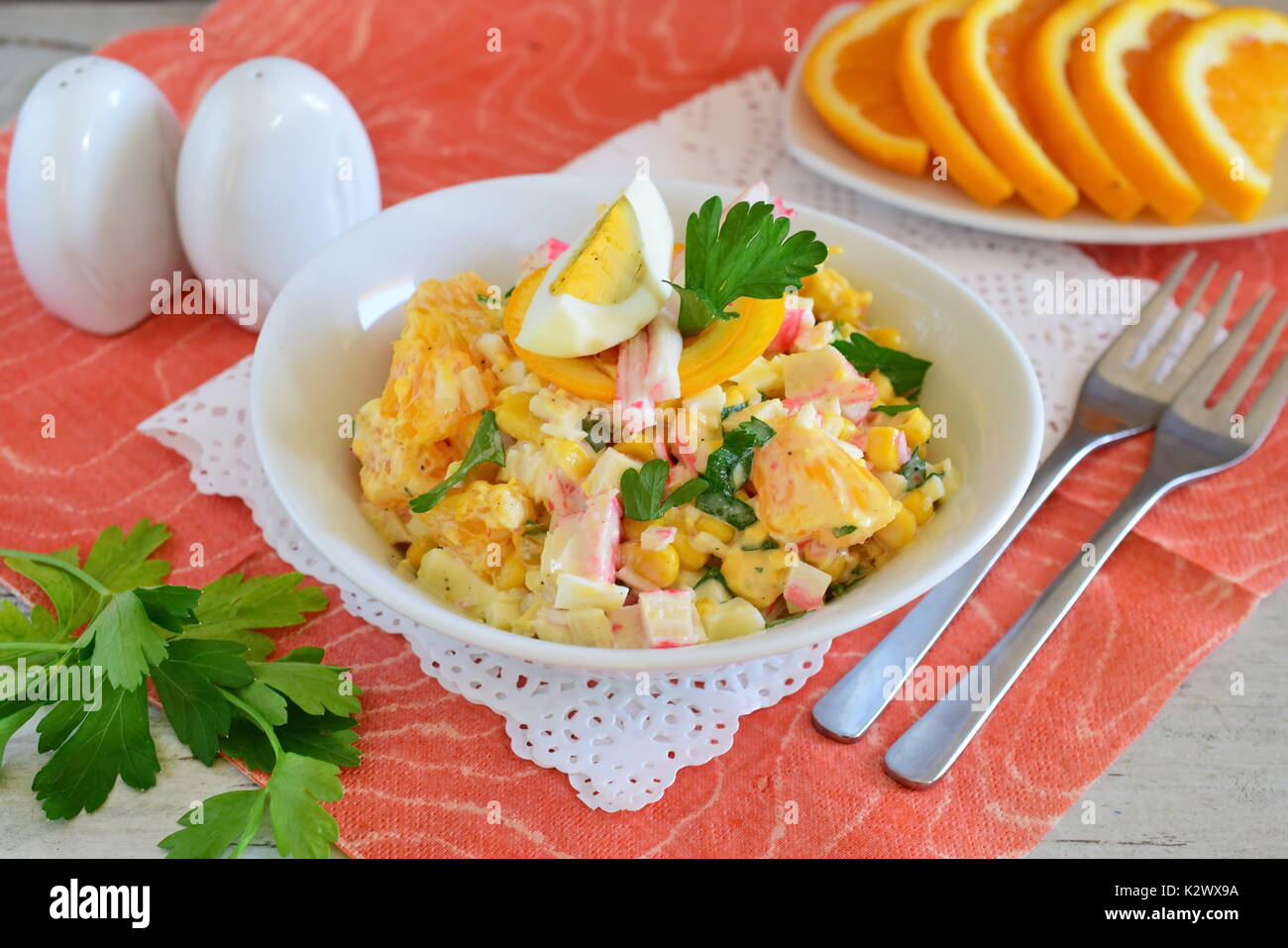 Salat aus Orange, Krabben Fleisch, Eier, Getreide mit Joghurt in einer weißen Schüssel auf einem Tuch Hintergrund serviert. Einfaches Essen. Gesunde Ernährung Konzept. Stockfoto