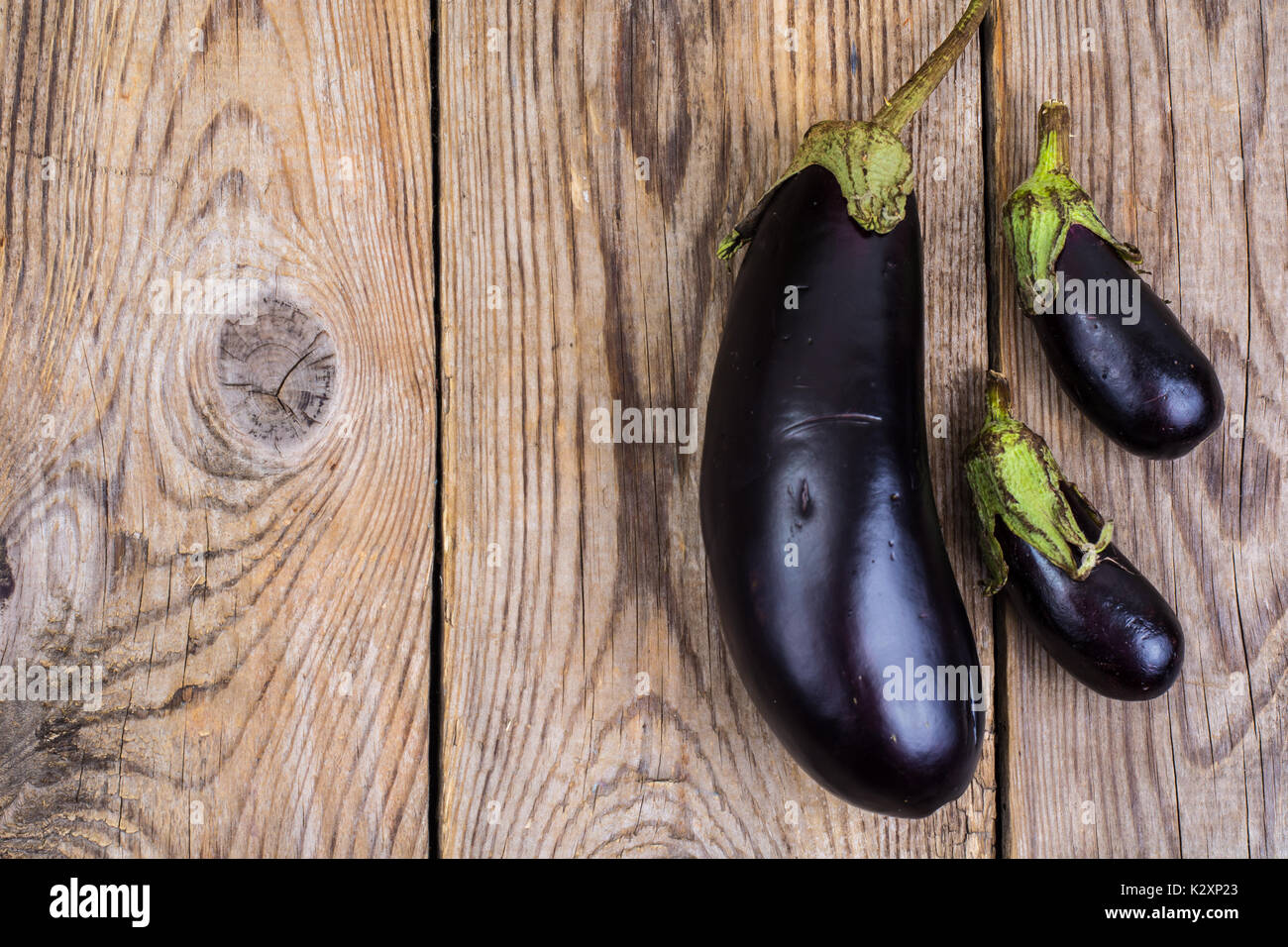 Ein großer und zwei kleine Aubergine auf Holz- Hintergrund. Studio Foto Stockfoto