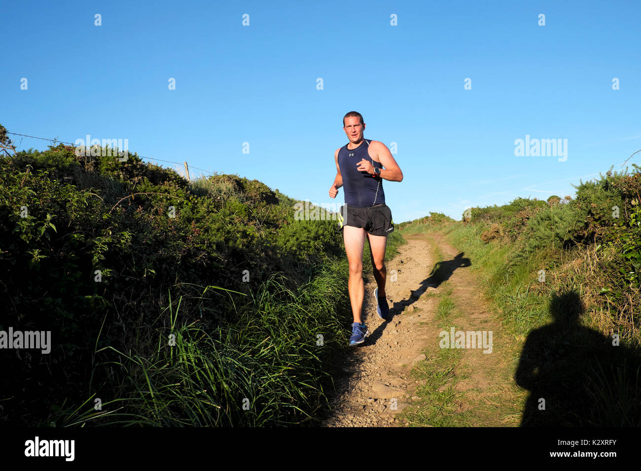 Mann laufen entlang der walisischen Küste im Sommer in kurzen Hosen, mit klaren blauen Himmel in der Nähe von St Davids in Pembrokeshire Wales, UK KATHY DEWITT Stockfoto