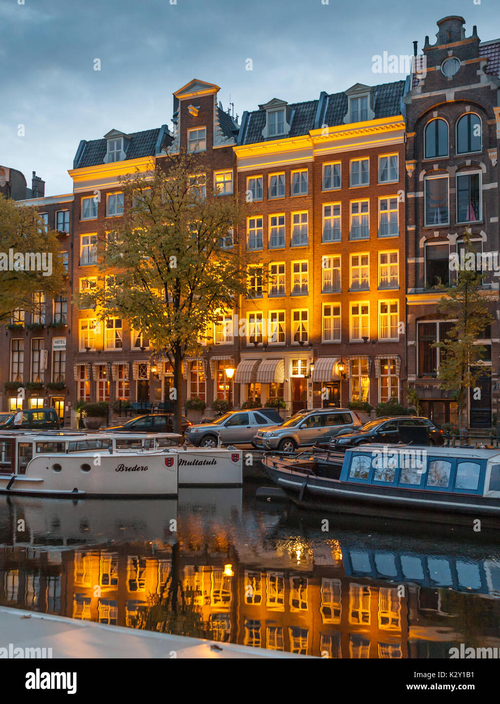 Amsterdam, Niederlande, 26. Oktober 2010: Boote und beleuchtete Grachtenhäuser bei Sonnenaufgang auf Singel Kanal Stockfoto