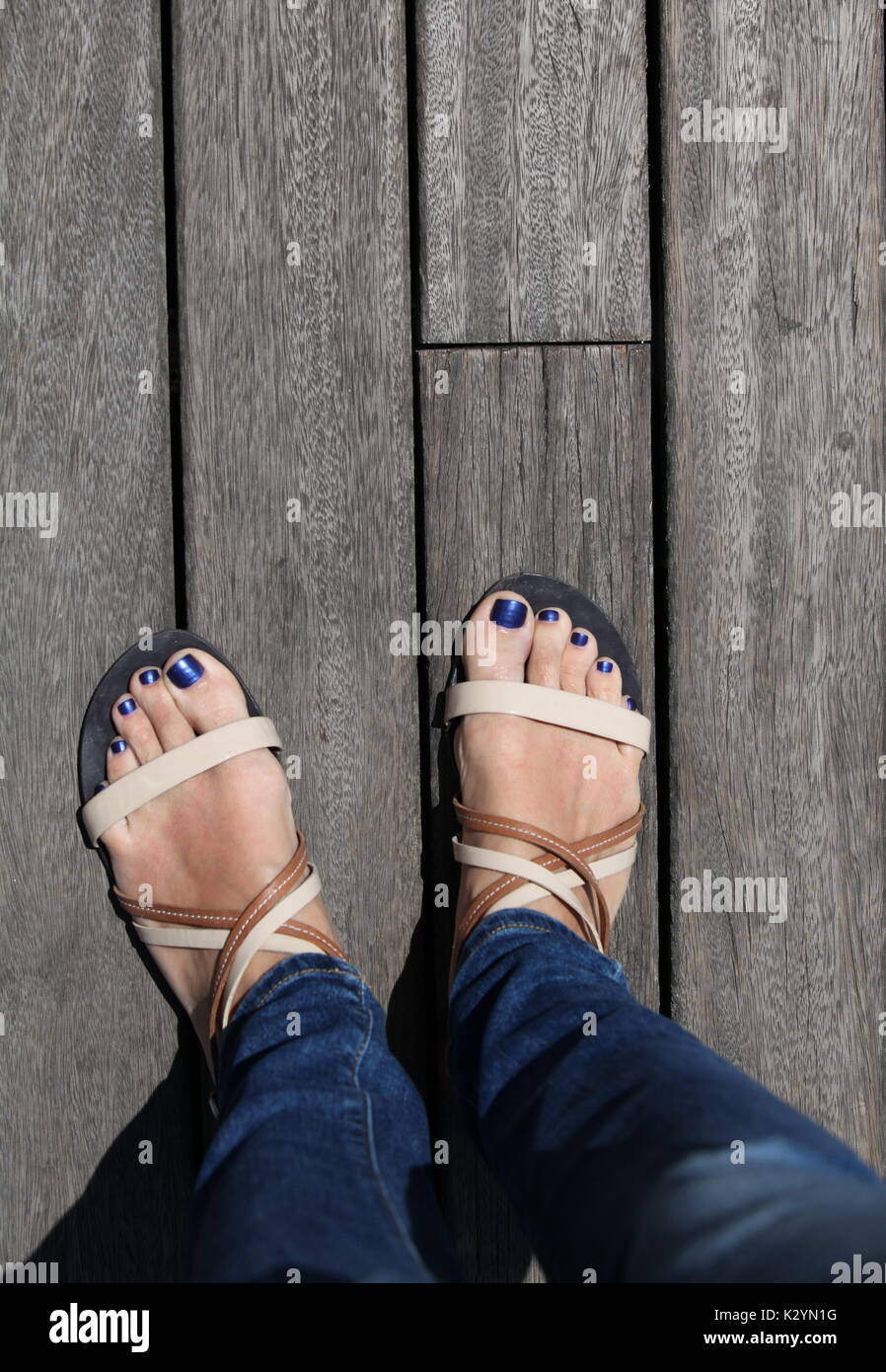 Weibliche Füße in Sandalen auf dem Boden Hintergrund Stockfoto