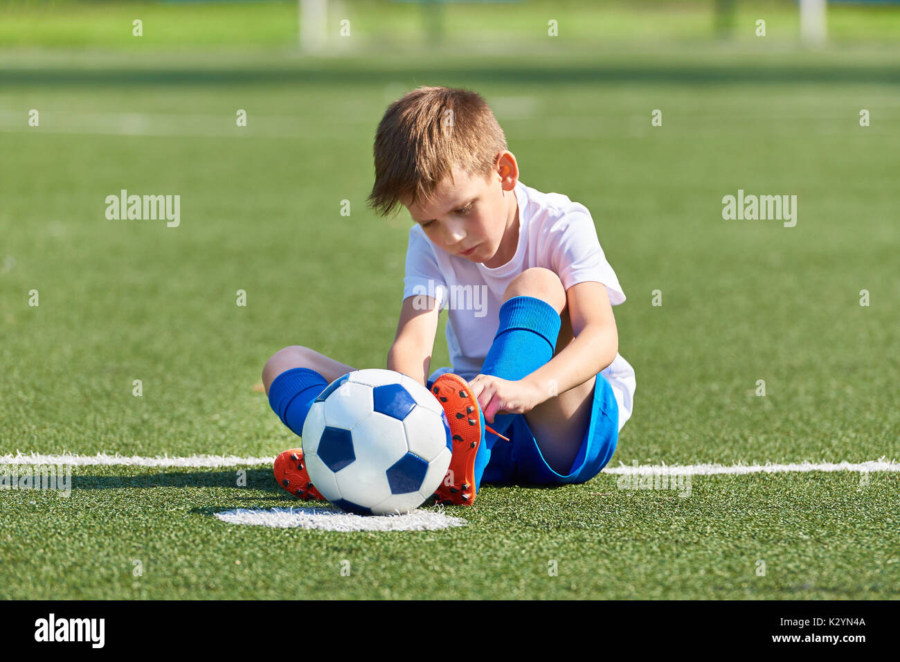 Jungen Fußball Fußball Binden der Schnürsenkel auf die Stiefel auf grünem Gras Stockfoto