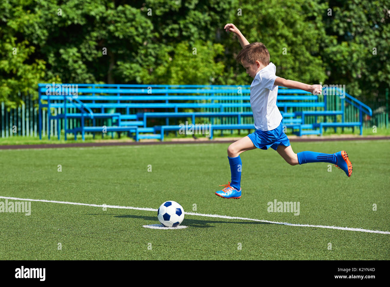 Junge Fußball-Spieler läuft mit dem Ball auf dem grünen Rasen des stadiumм Stockfoto