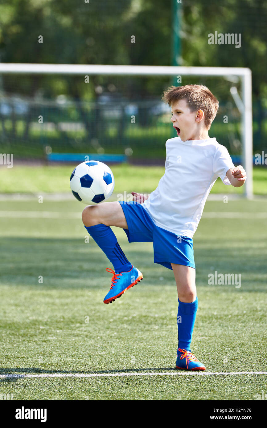 Jungen Fußball spielen mit Ball auf Fußball-Stadion Stockfoto