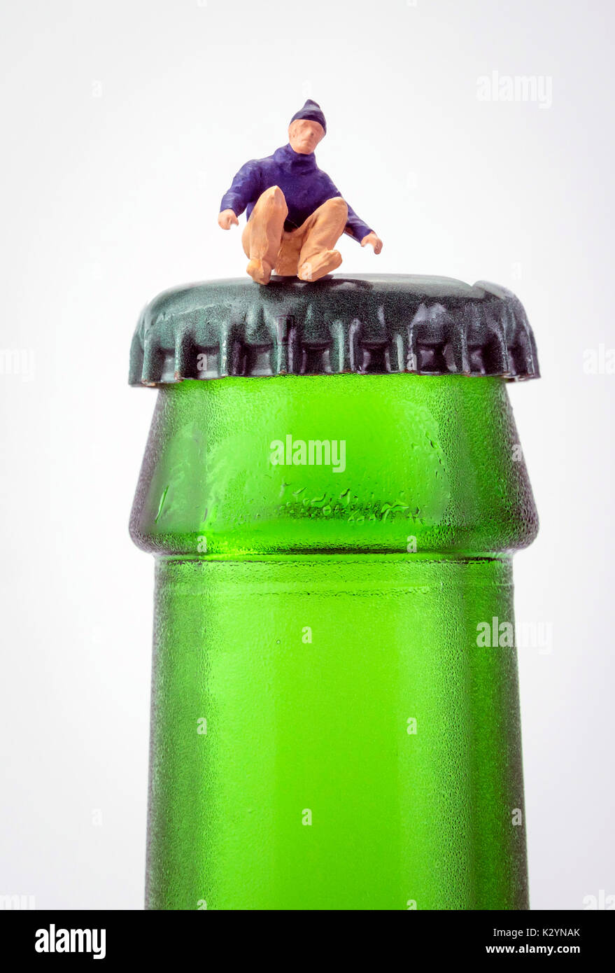 Miniatur Mann saß oben auf der eine Flasche Bier auf weißem Hintergrund Stockfoto