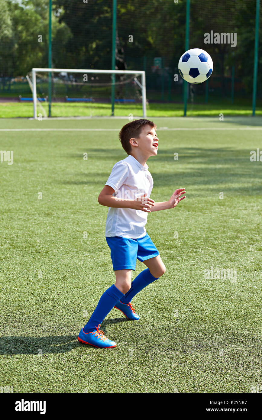 Jungen Fußball spielen mit Ball auf Fußball-Stadion Stockfoto