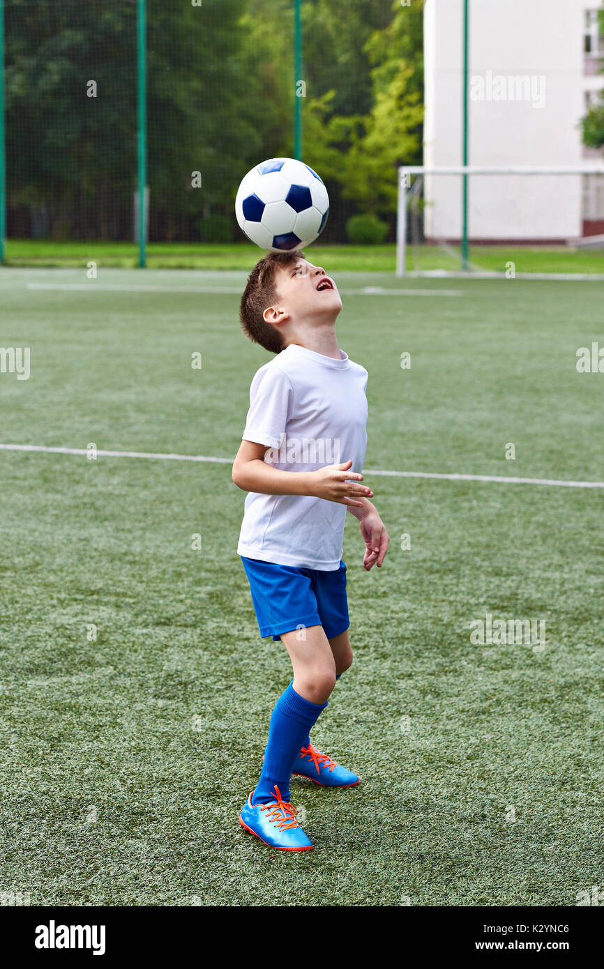 Jungen Fußball spielen mit Ball auf Fußball-Stadion Stockfoto