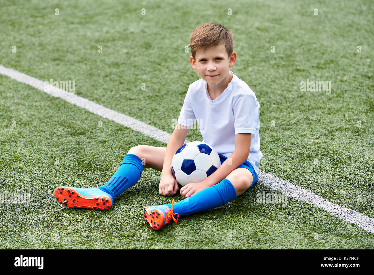 Jungen Fußball Fußball mit Kugel sitzt auf einem grünen Gras Stockfoto