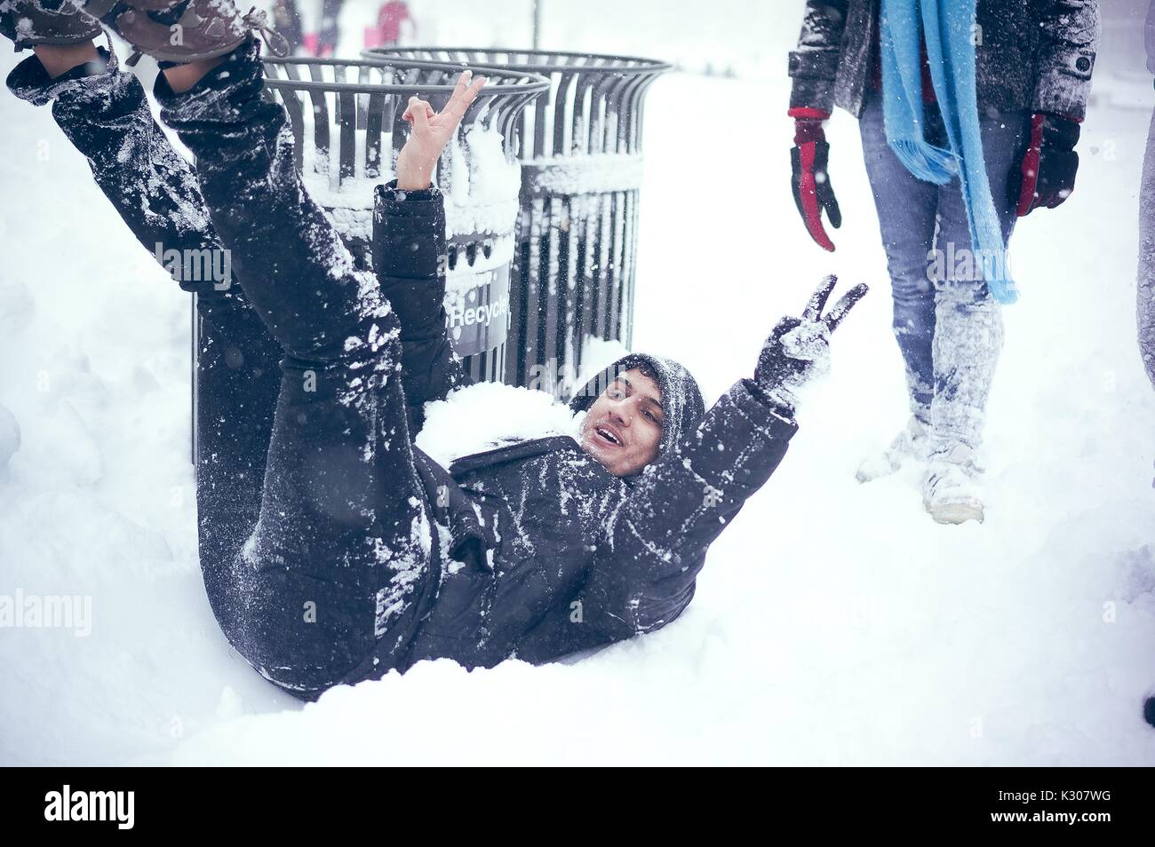 Ein Student Lächeln und sitzt im Schnee auf dem Rücken mit Armen und Beinen in der Luft nach unten die verschneite Treppe während einer Snow Day an der Johns Hopkins University, Baltimore, Maryland, 2016 glitt. Stockfoto